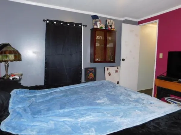 a bedroom with a bed and a flat tv screen on dresser