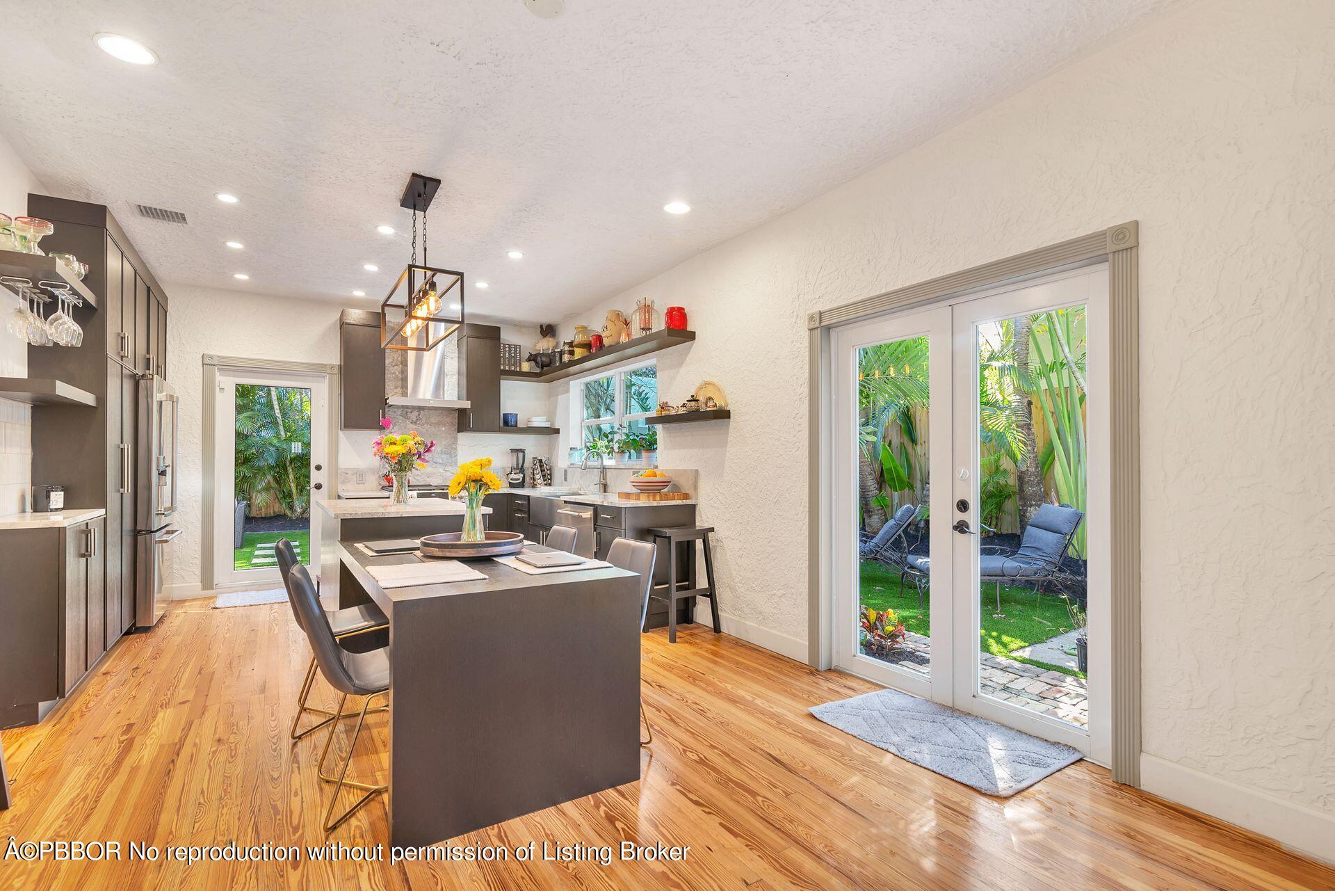 612 Upland Road West Palm Beach, FL 33401 - Photo 9 of 24 a dining room with kitchen island stainless steel appliances furniture a floor to ceiling window and wooden floor