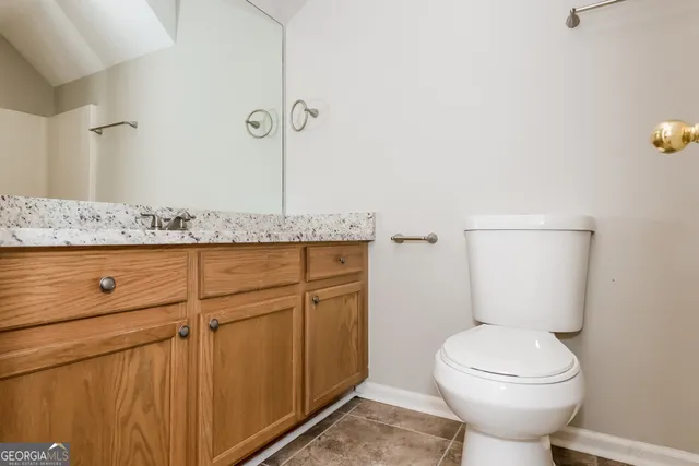 a bathroom with a granite countertop toilet and a sink