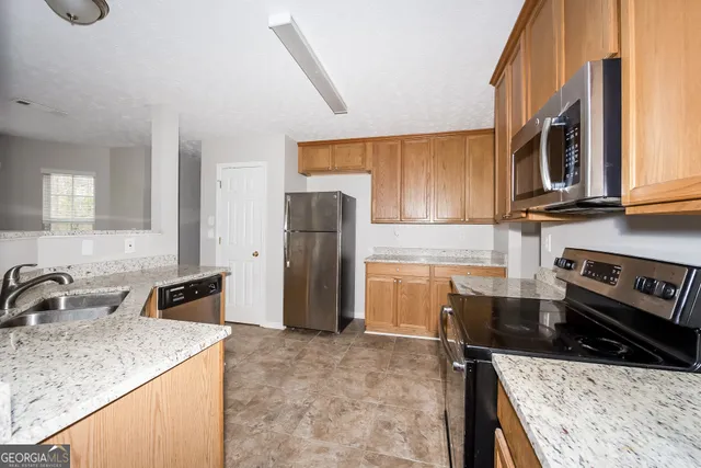 a kitchen with granite countertop a sink stove and refrigerator