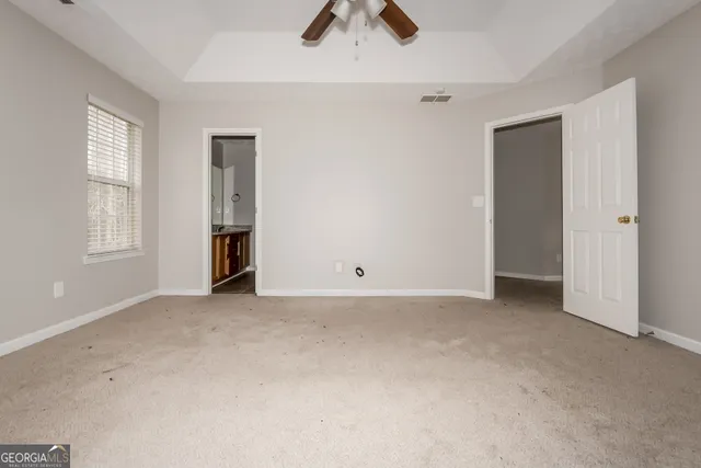 an empty room with chandelier fan and windows