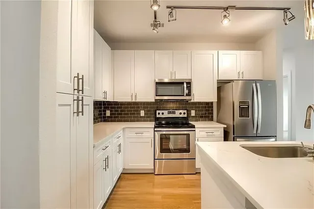 a kitchen with stainless steel appliances a refrigerator sink and microwave