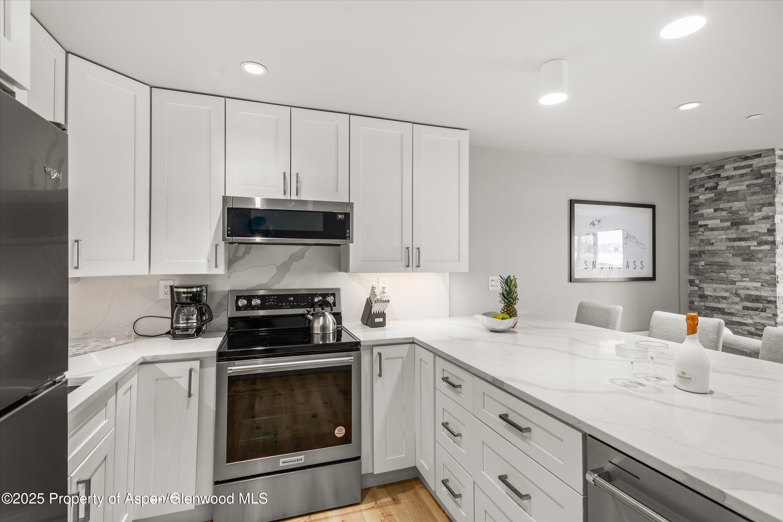 150 Carriage Way, Unit 3 Snowmass Village, CO 81615 - Photo 5 of 12 a kitchen with stainless steel appliances a stove a sink and a microwave