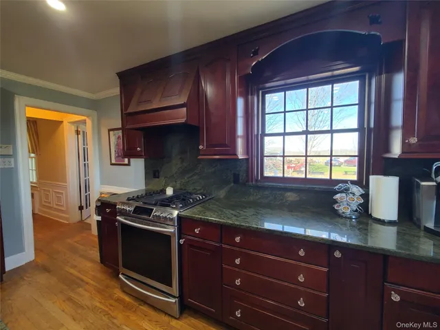 a kitchen with granite countertop wooden cabinets stainless steel appliances and a window