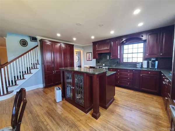 a kitchen with stainless steel appliances granite countertop a stove a refrigerator a sink and dishwasher wooden cabinets with wooden floor