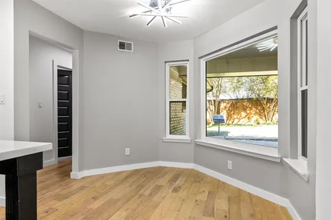 en view of an empty room with a window and wooden floor