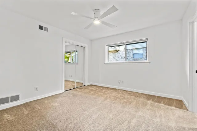 an empty room with windows and ceiling fan