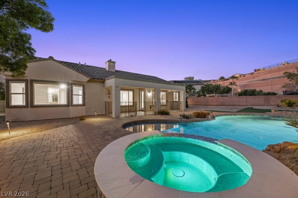 2125 De Rouge Avenue Henderson, NV 89044 - Photo 12 of 96 An inviting pool and spa beckon under the soft twilight, perfectly complementing the home's illuminated patio area.