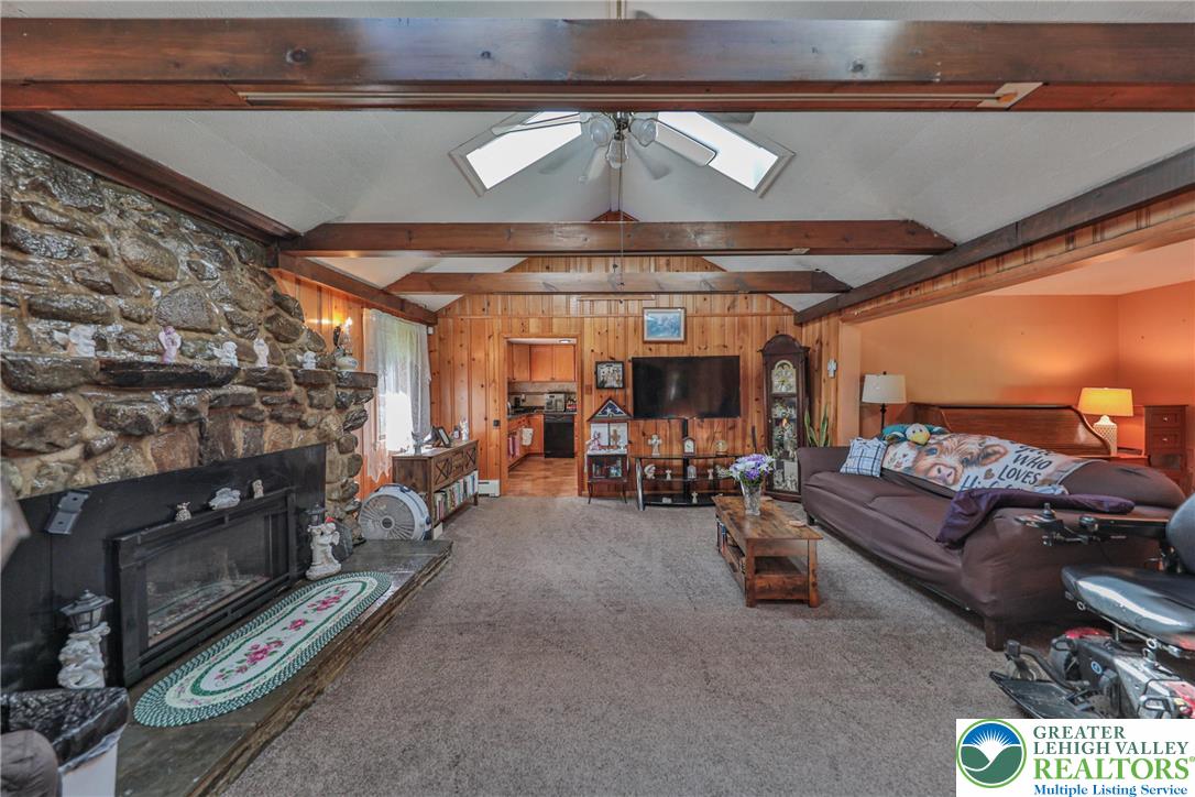 331 Cranberry Creek Road Cresco, PA 18326 - Photo 16 of 95 A rustic living area with exposed wood beams features a striking stone fireplace and a comfortable ambiance.