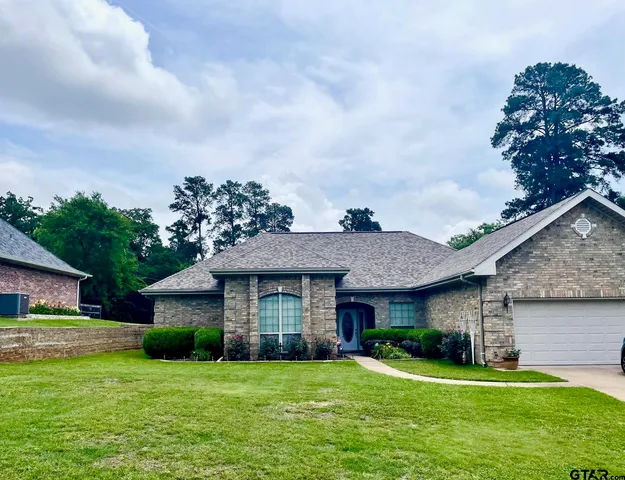 a view of a house with a big yard plants and large trees