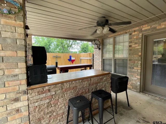a view of a patio with table and chairs potted plants and floor to ceiling window