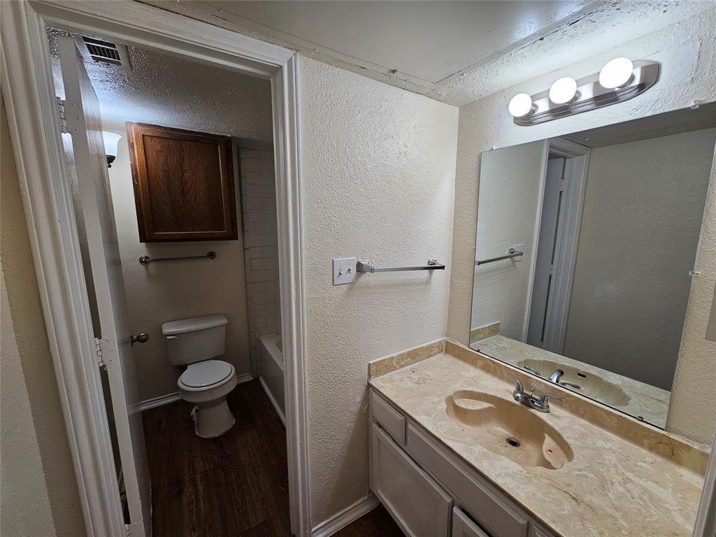 9823 Walnut Street, Unit 208 Dallas, TX 75243 - Photo 9 of 16 a bathroom with a granite countertop sink a toilet and mirror