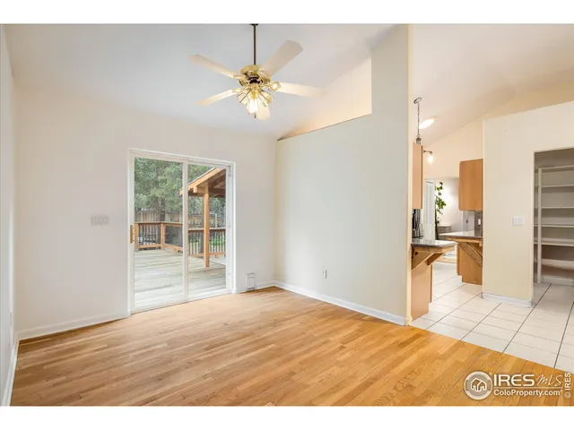 a view of a kitchen & an empty room with wooden floor