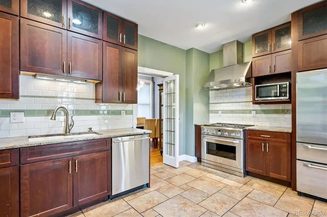a kitchen with stainless steel appliances granite countertop a sink stove refrigerator and cabinets