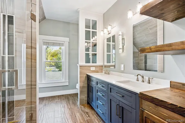a spacious bathroom with a double vanity sink a mirror and a shower