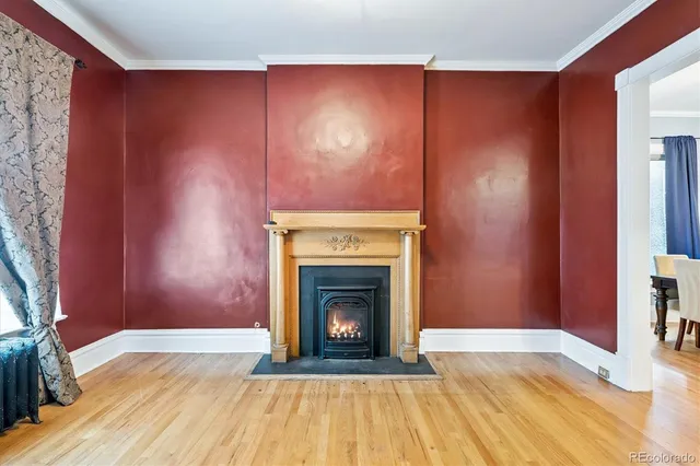 a view of an empty room with wooden floor and a fireplace