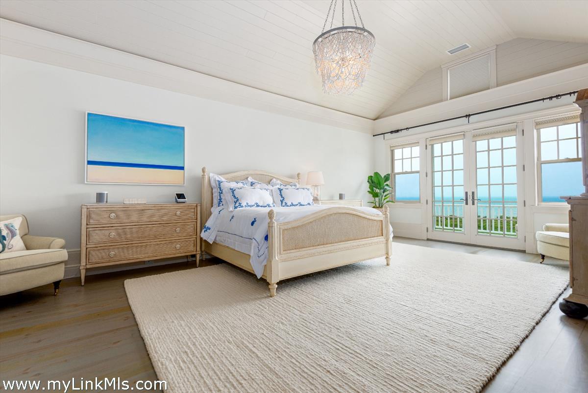 37 Sankaty Head Road Nantucket, MA 02554 - Photo 36 of 65 a spacious bedroom with a bed a couch and large window