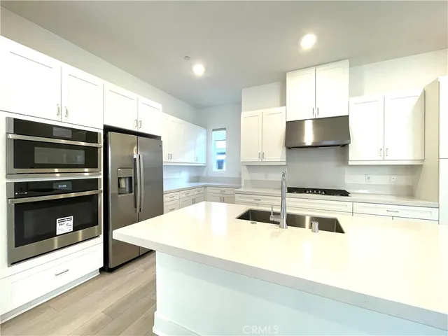 a view of empty room with wooden floor and kitchen view