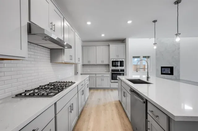 a kitchen with stainless steel appliances a sink a stove top oven a counter space and cabinets