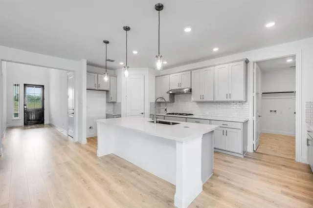 a large kitchen with stainless steel appliances kitchen island a stove a refrigerator a sink dishwasher and a oven with white cabinets