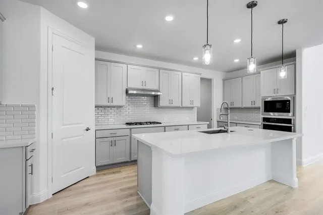 a kitchen with stainless steel appliances granite countertop a stove a sink and a refrigerator with wooden floor