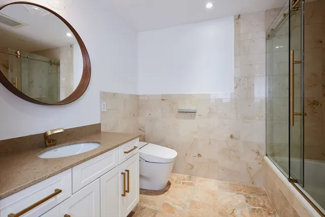 a bathroom with a granite countertop toilet a sink and a mirror