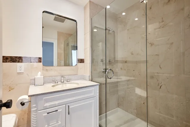 a bathroom with a shower sink vanity and mirror