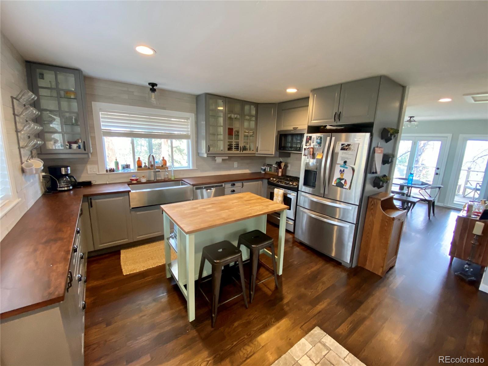 44 Pine Road Golden, CO 80401 - Photo 5 of 35 a kitchen with stainless steel appliances a refrigerator a stove a sink dishwasher and a dining table with wooden floor