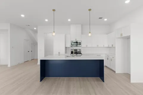 a view of kitchen with stainless steel appliances granite countertop a sink refrigerator and wooden floor