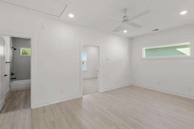 an empty room with wooden floor and windows