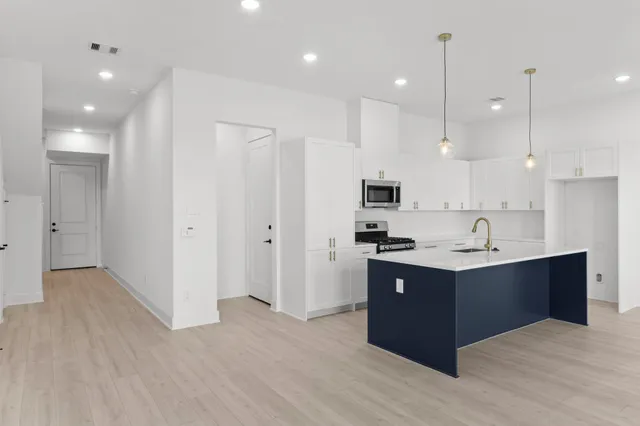 a kitchen with stainless steel appliances granite countertop a sink stove and wooden floor