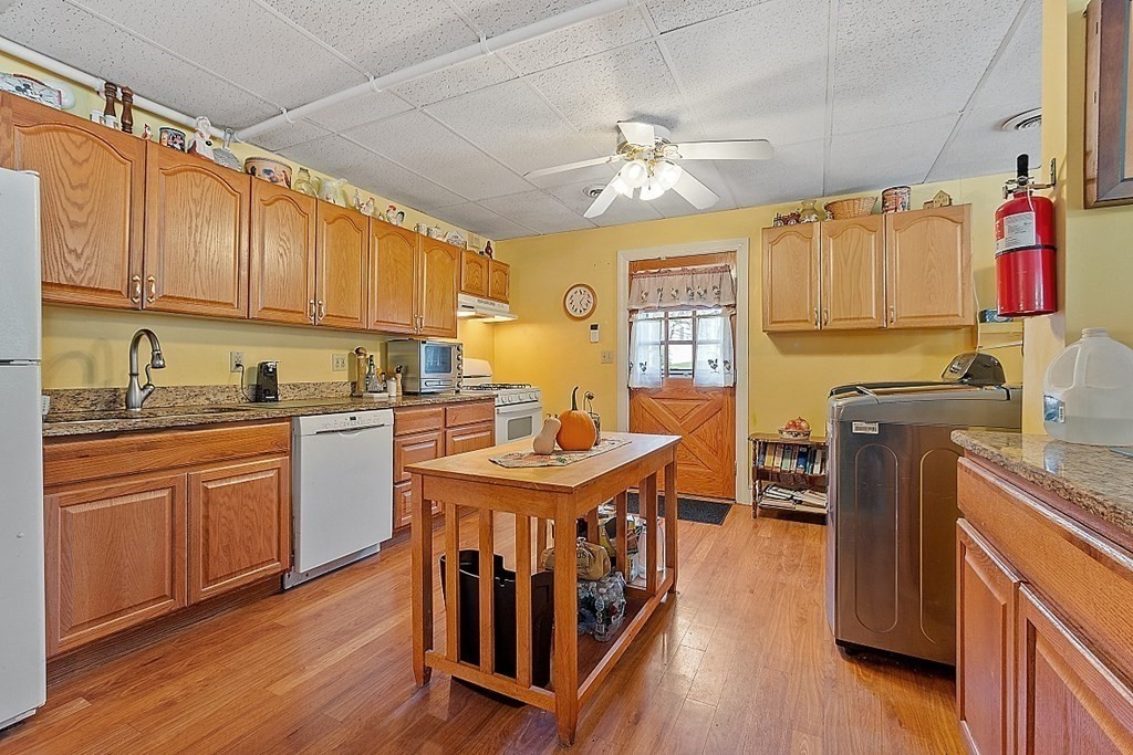 479-483 Gleasondale Road Stow, MA 01775 - Photo 21 of 40 a kitchen with stainless steel appliances granite countertop a stove top oven a refrigerator a sink dishwasher and white cabinets with wooden floor