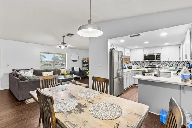 a kitchen with kitchen island a dining table chairs stainless steel appliances and cabinets