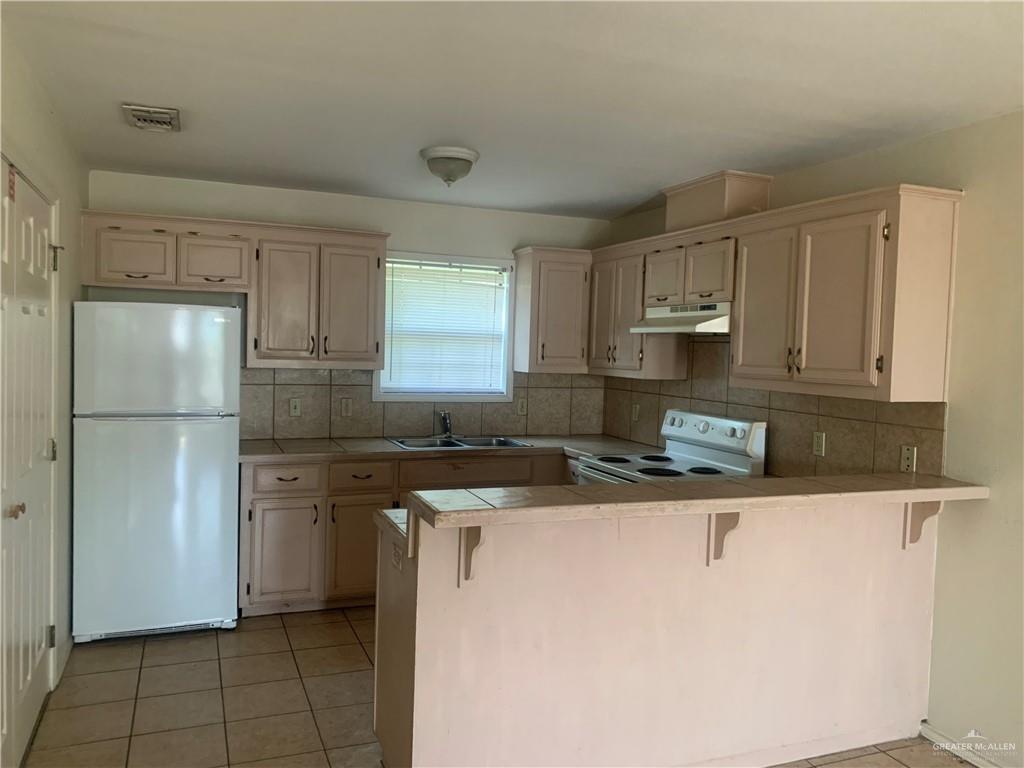 918 East Preston Avenue, Unit 4 Pharr, TX 78577 - Photo 2 of 10 a kitchen with stainless steel appliances granite countertop a refrigerator sink stove and white cabinets