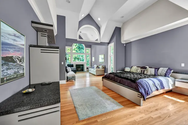 a spacious bedroom with a bed a mirror on dresser and a large window