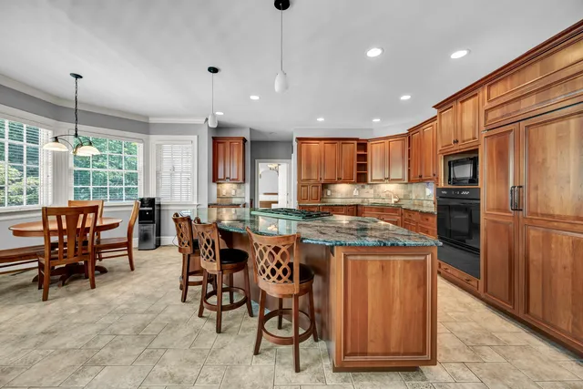 a kitchen with stainless steel appliances granite countertop dining table chairs refrigerator and sink