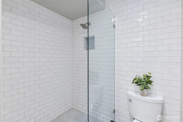 a bathroom with a toilet a sink a mirror and shower