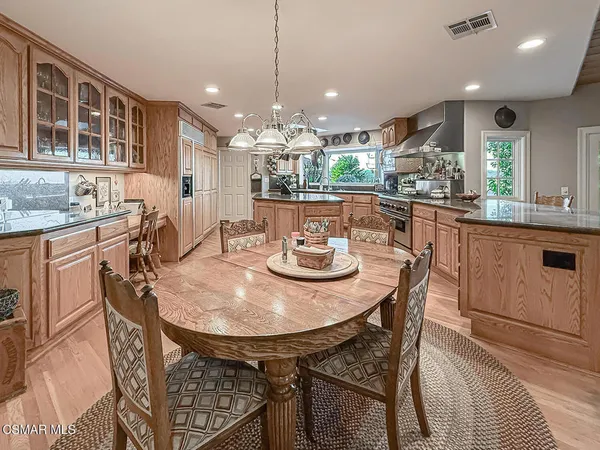a kitchen with stainless steel appliances granite countertop a sink a stove cabinets and a dining table