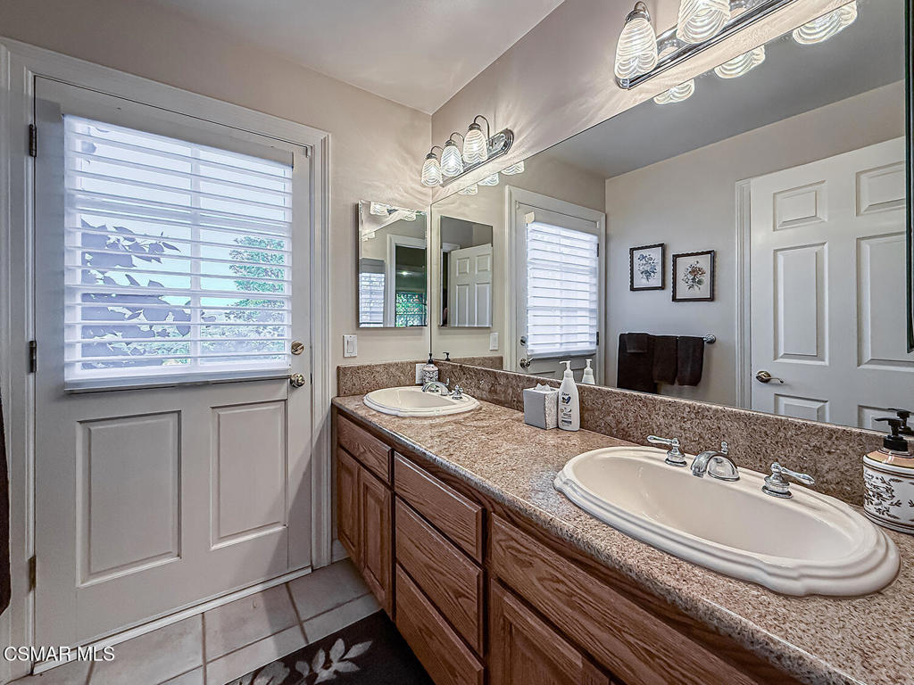 24525 Desert Avenue Newhall, CA 91321 - Photo 45 of 76 a bathroom with a granite countertop sink a mirror and a bathtub