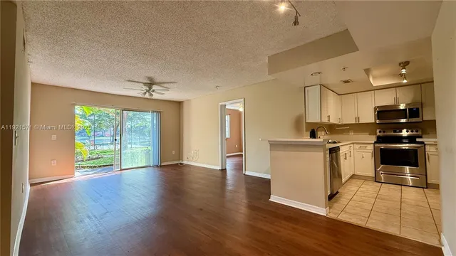 a kitchen with granite countertop a stove a sink and white cabinets with wooden floor next to windows