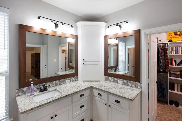 a bathroom with a granite countertop double vanity sink and a mirror