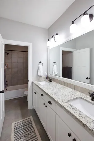 a bathroom with a granite countertop double vanity sink and mirror