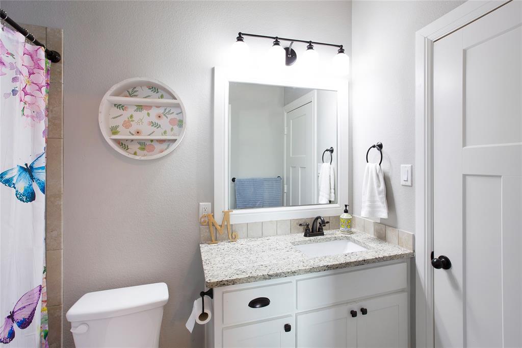 7230 Woodstream Road Midlothian, TX 76065 - Photo 24 of 26 a bathroom with a granite countertop sink a toilet and a mirror