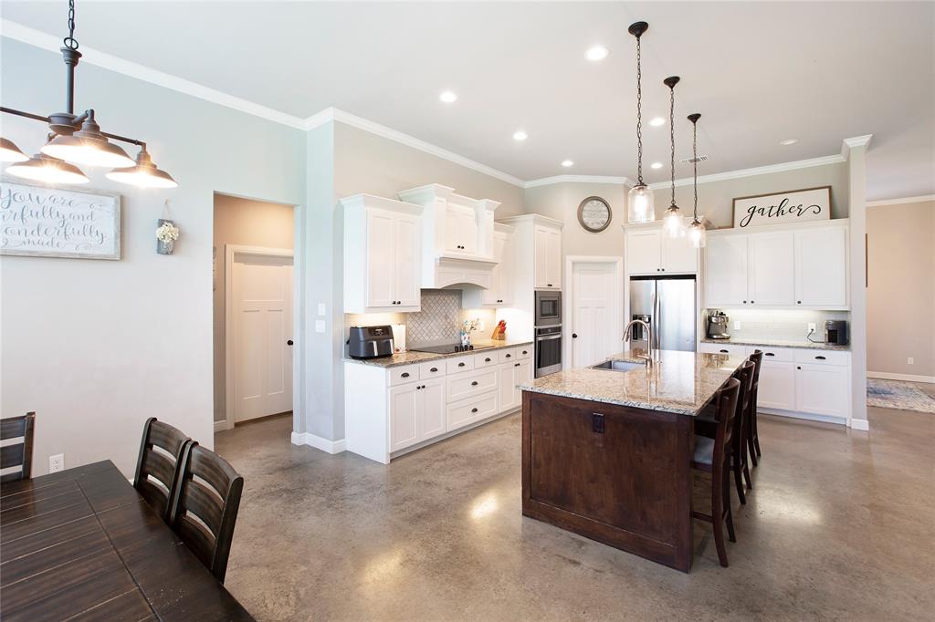 7230 Woodstream Road Midlothian, TX 76065 - Photo 9 of 26 a large white kitchen with a refrigerator a sink dishwasher a dining table and chairs with wooden floor