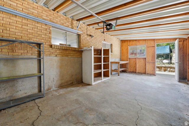 1486 3rd Street Ogden, UT 84404 - Photo 19 of 26 Spacious garage with exposed brick walls, concrete flooring, and an overhead garage door mechanism