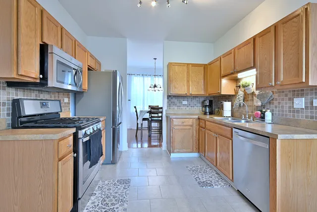 a kitchen with stainless steel appliances granite countertop a stove top oven a sink a refrigerator and white cabinets