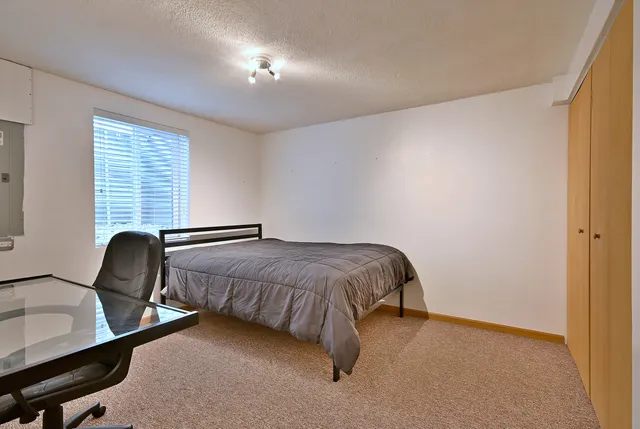 a bedroom with a bed chair and windows