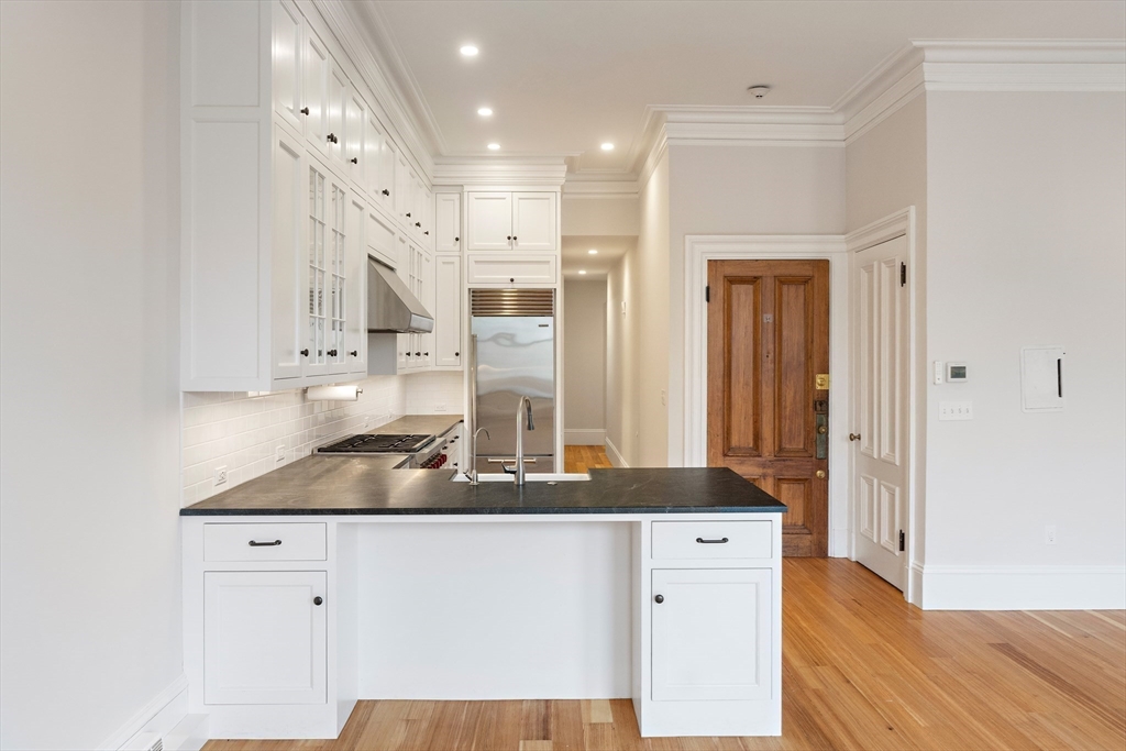 64 Commonwealth Avenue, Unit 5 Boston, MA 02116 - Photo 10 of 24 a kitchen with cabinets appliances and a wooden floor