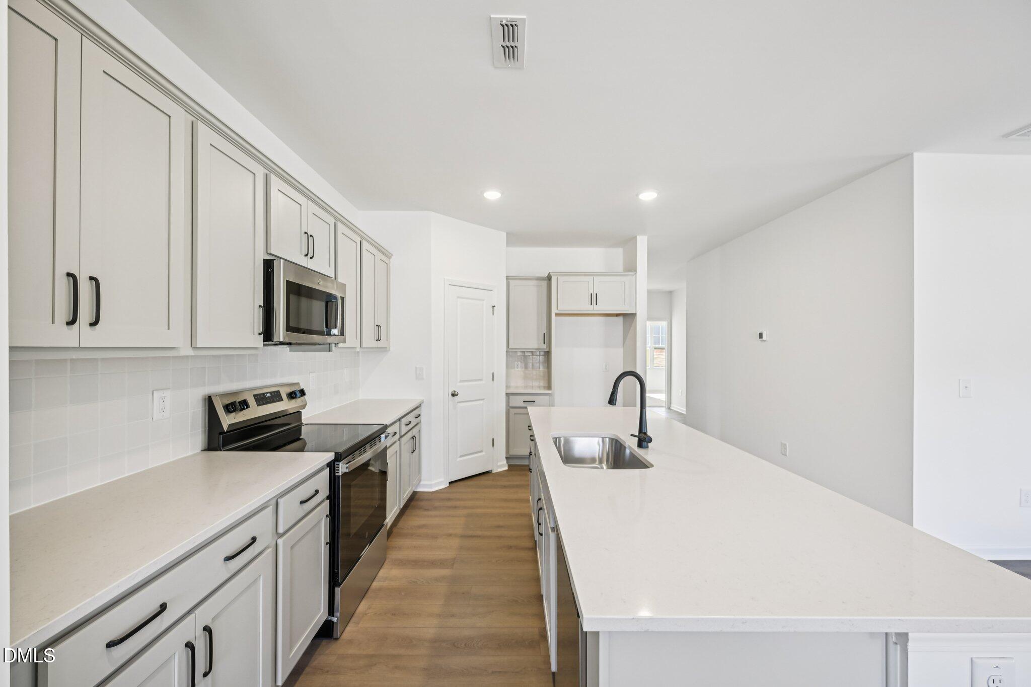 11766 Salers Loop Middlesex, NC 27557 - Photo 15 of 55 a kitchen with stainless steel appliances a sink a stove a microwave a sink a refrigerator and cabinets