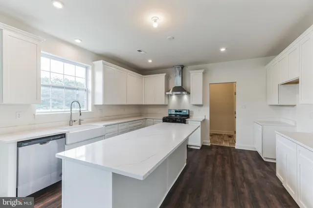 a large kitchen with a center island wooden floor and stainless steel appliances